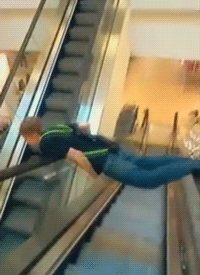 gifs - boy balances himself between escalator banister