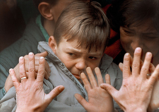 A father’s hands press against the window of a bus carrying his tearful son and wife to safety during the Siege of Sarajevo, November 10, 1992