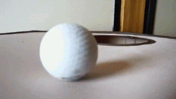 Caturday gif of a cat jumping through a hole to play with a ball