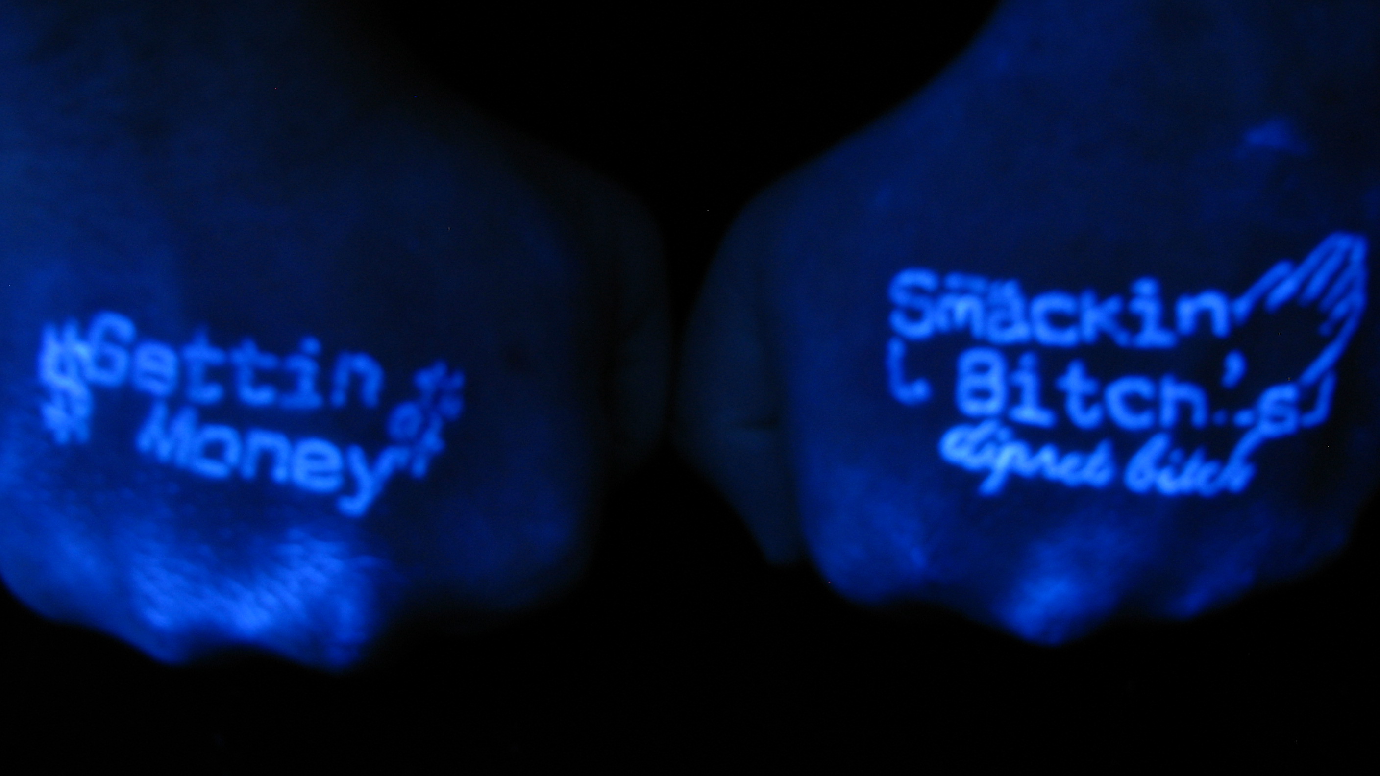 "Smackin Bitches" on one hand, and "Gettin Money" on the other hand done in Invisible Black light ink