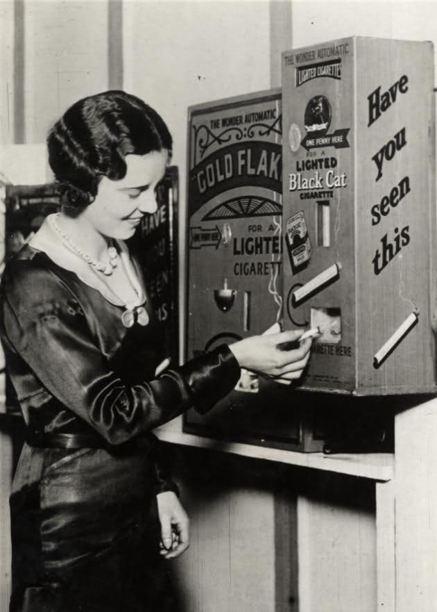 A vending machine that sold already lit cigarettes for a penny. England, 1931.