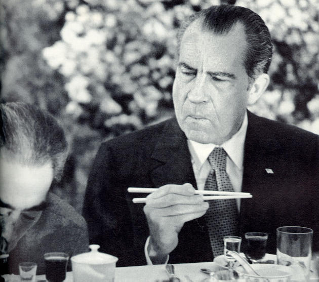 President Richard Nixon trying to figure out how to use chopsticks while visiting in China. 1972.