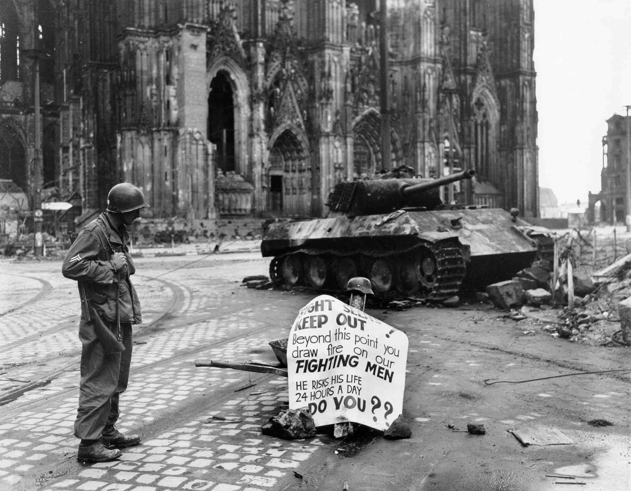 Corporal Luther E. Boger of US 82nd Airborne Division reading a warning sign, Cologne, Germany, 4th April 1945.