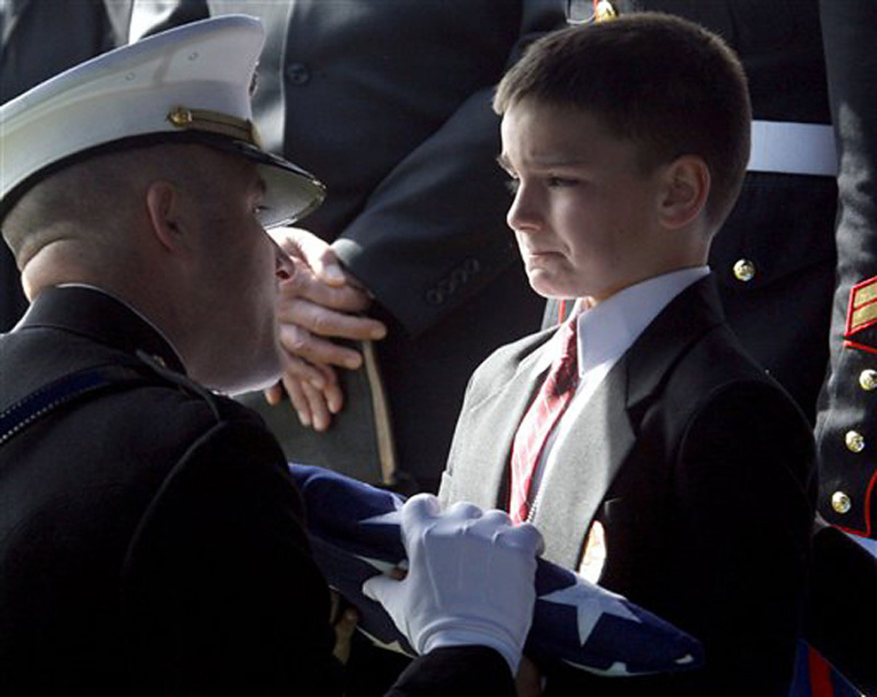 Eight-year-old Christian Golczynski accepts the flag for his father, Marine Staff Sgt. Marc Golczynski, during a memorial service. Marc Golczynski was shot on patrol during his second tour in Iraq (which he had volunteered for) just a few weeks before he was due to return home.
