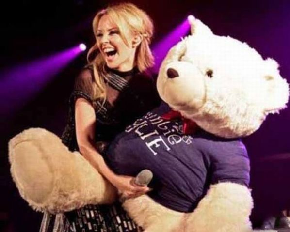 Kylie Minogue With Microphone. Hard to believe Facebook would not permit this harmless image of Kylie and her massive teddy bear.
