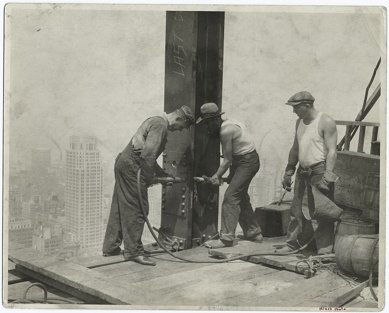 Three workers securing a rivet