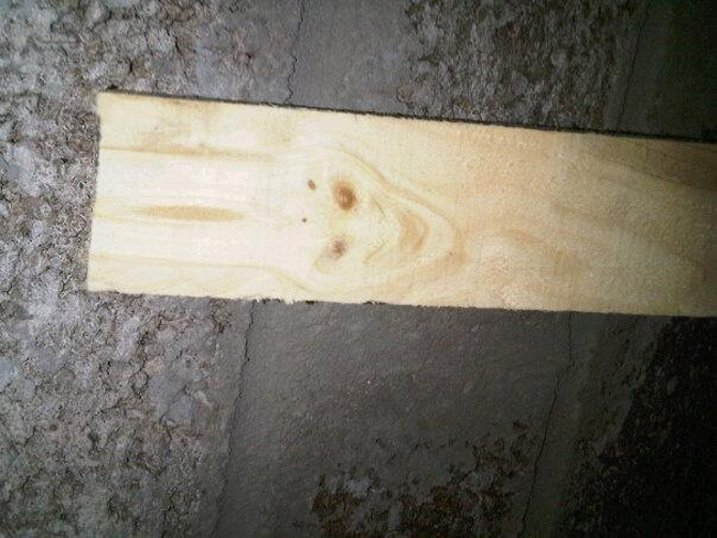 A demonic trollface appears on pieces of lumber.