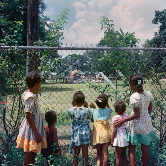Black children looking at for whites only playground through the fence, Alabama, 1956