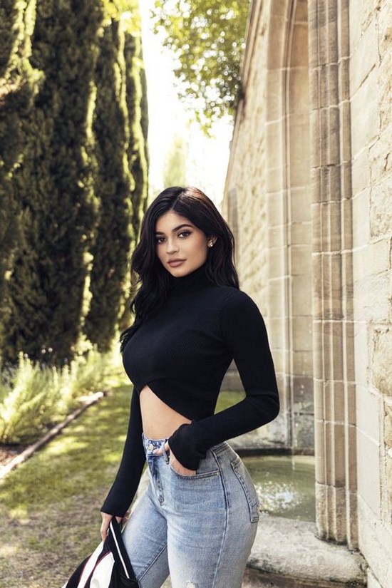 Kylie Jenner in long sleeve shirt that doesn't cover her stomach and jeans that accentuate her figure in a very 80's way