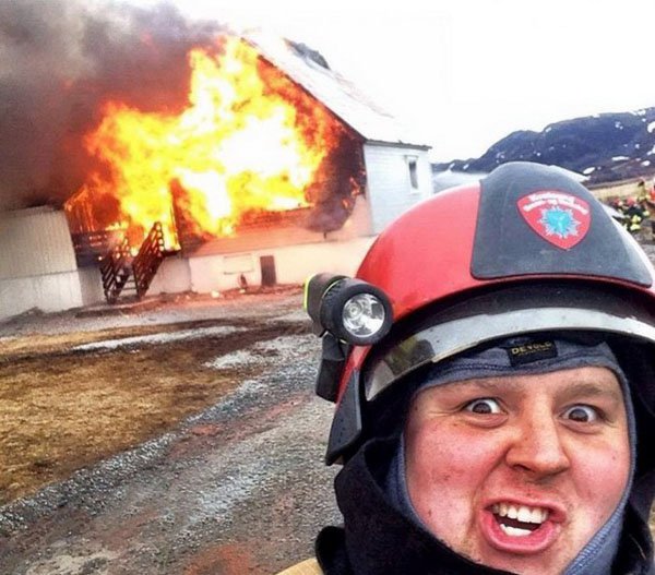 Funny picture of a fire man posing by a burning building