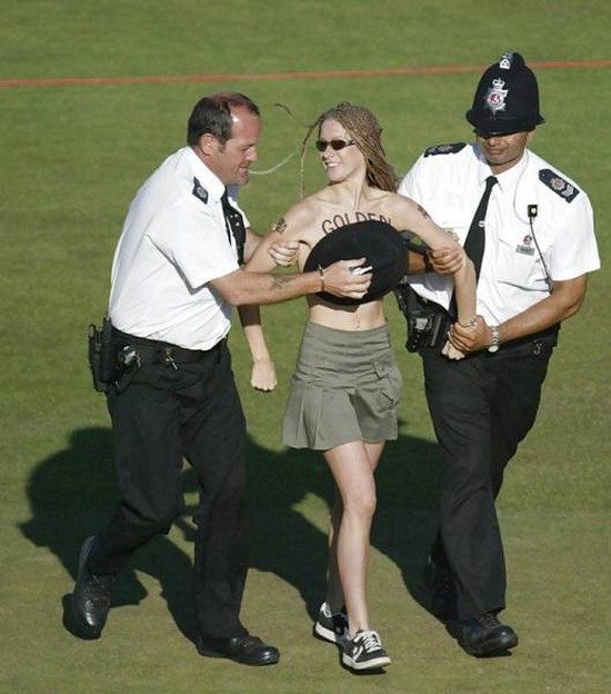 Funny picture of security escorting a topless woman off the field.