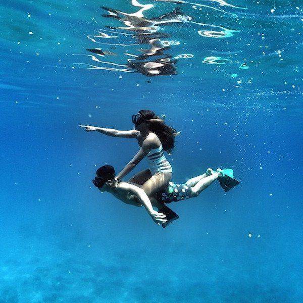 Cool underwater pic of a girl riding a boy like a horse and pointing to where she wants to go.