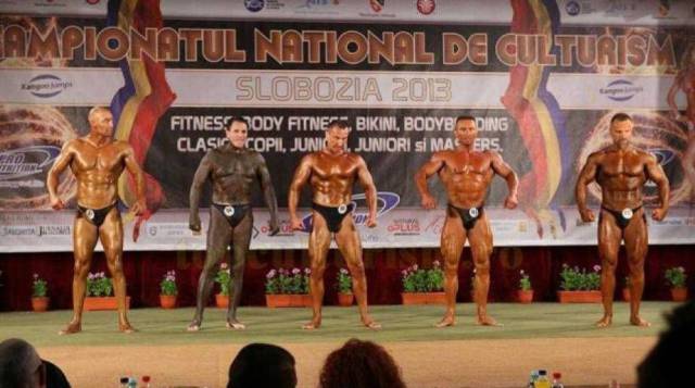 Funny picture of a work out competitions and one of the dudes is very dark but not his face.