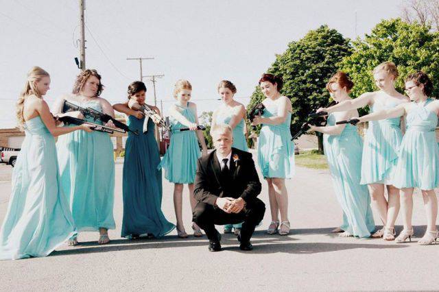 Wedding photo of all the girls pointing their assault rifles at the groom.