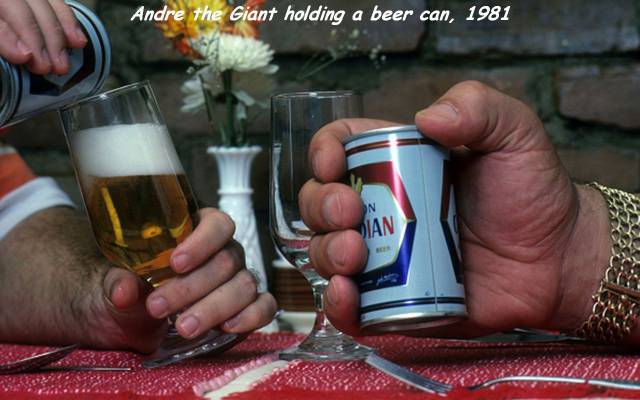 Andre The Giant holding a can of beer that looks tiny in his massive hands.