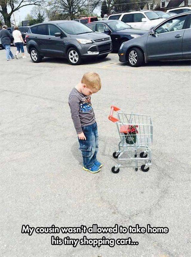 Kid all sad in a parking lot because he can't take home the tiny shopping cart from the grocery store.