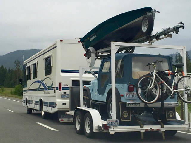 Weekend ready photo of an RV pulling a jeep and a boat.