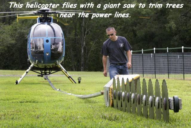 helicopter saw - This helicopter flies with a giant saw to trim trees i near the power lines.