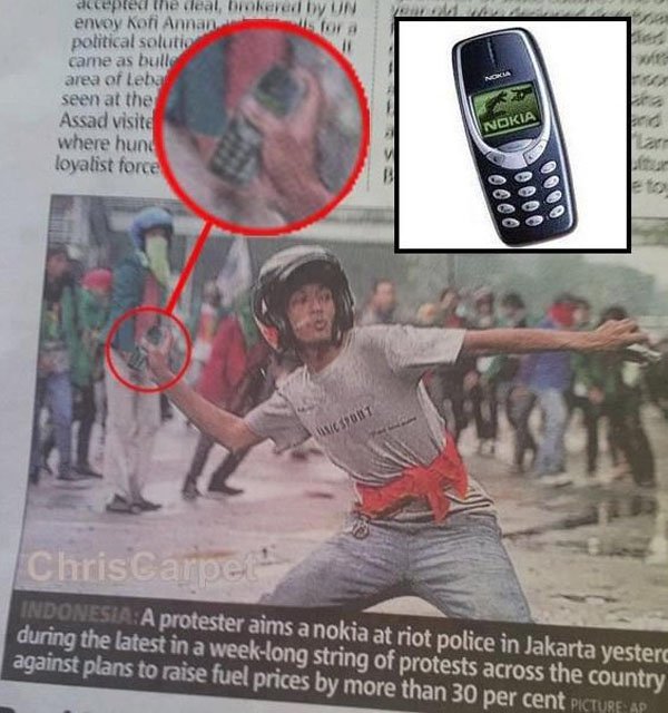 Riot photo of man throwing a Nokia phone at police