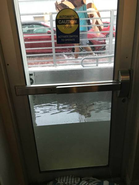 funny picture of an automatic door that is holding back 2 feet high water from entering the premises