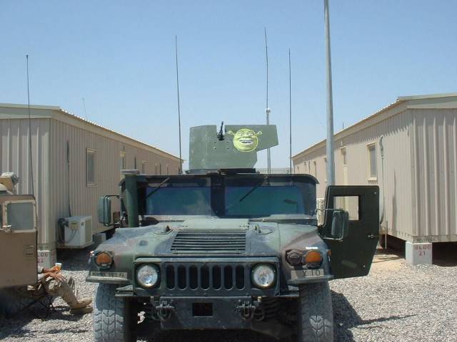 Military humvee with a sticker of Shrek up against the 50 calibre gun mounted on the top