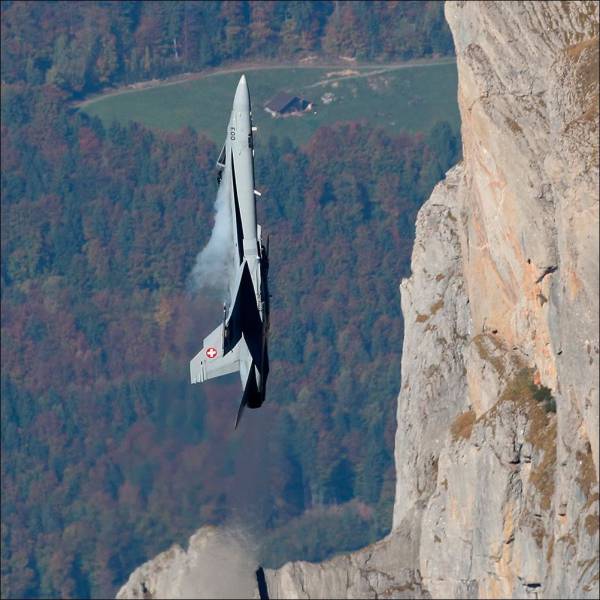 f-15 flying straight upwards right alongside a cliff face.