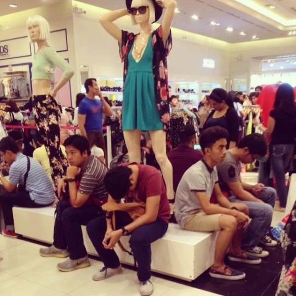 Funny pic of really bored travellers under a mannequin woman.