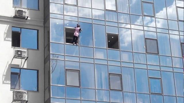 woman casually going out her window of a high-rise building.