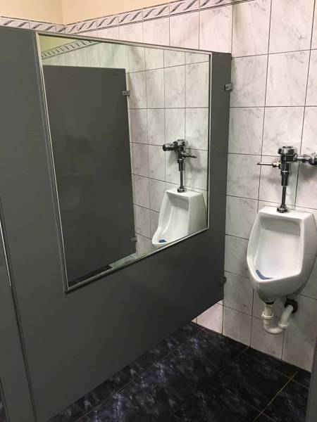 Urinal with massive mirror next to it.