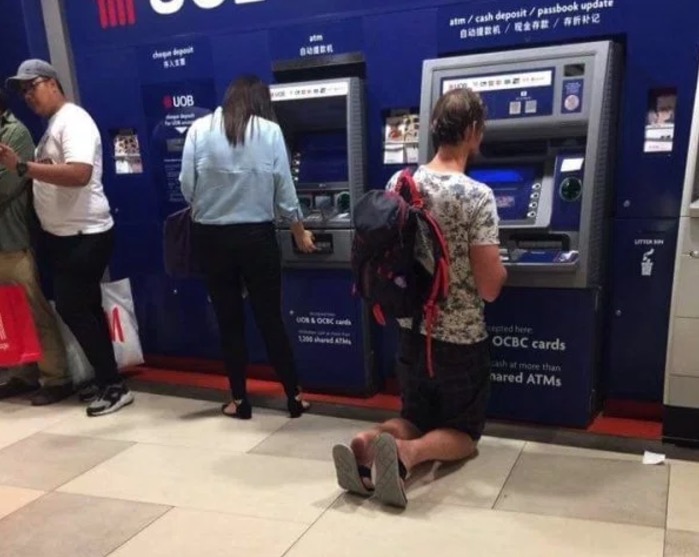 Tall man at an ATM on his knees