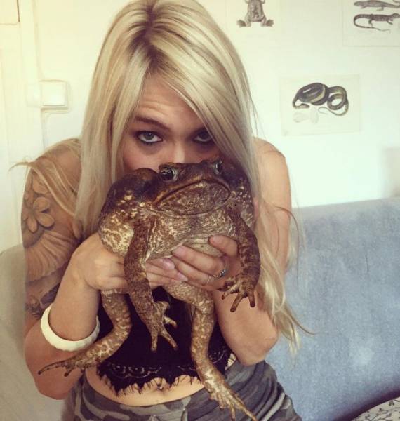 Blonde woman kissing a huge frog.