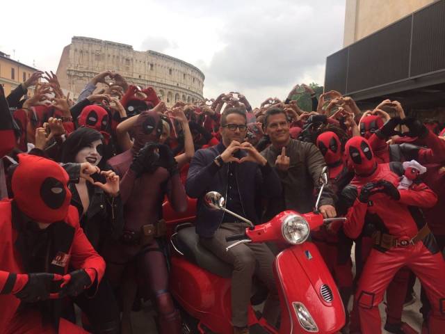 deadpool stars surrounded by fans dressed as deadpool in Rome, giving the camera the finger and a heart