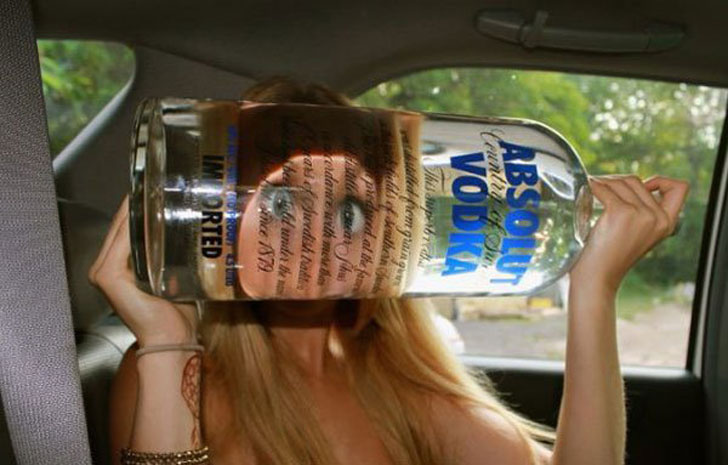 girl making funny face warped by vodka bottle