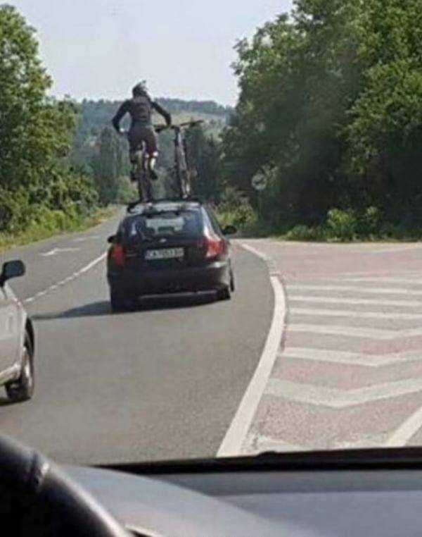 guy standing on top of his car while driving down the road