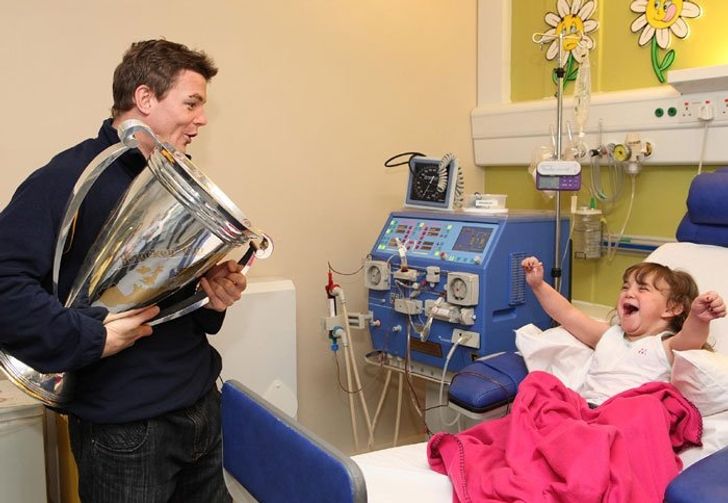 Brian O’Driscoll, an Irish rugby player, is visiting a young girl in the hospital with the Heineken cup