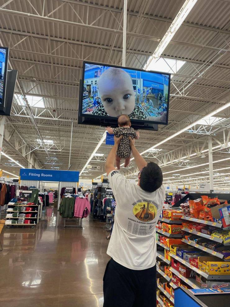 funny pics - dad holding his baby up to store security camera tv