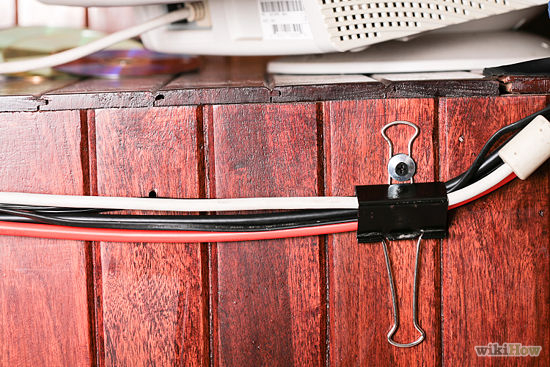 Keep cords off the floor and out of sight by attaching a couple binder clips to the back of your desk or entertainment center.