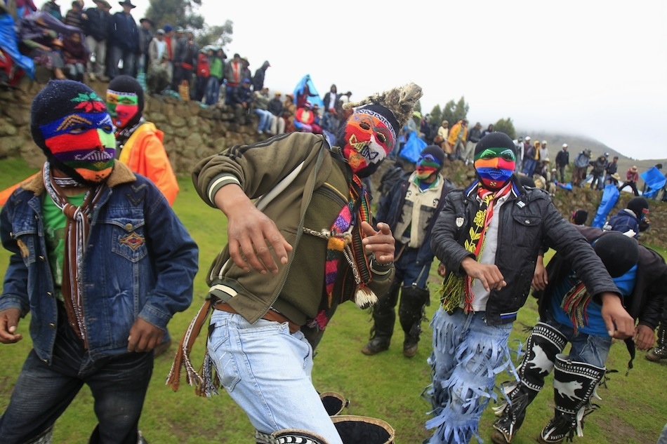 Andean men wearing masks dance while entering the ring to participate in fight