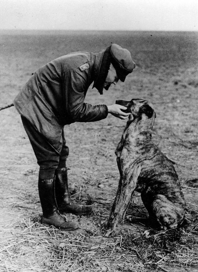 Manfred von Richthofen, aka The Red Baron, petting his dog on an airfield.