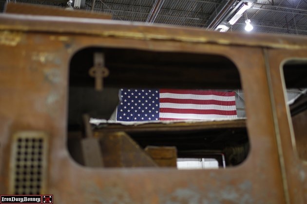 An American flag is visible through the rusted window of a destroyed Fire Engine