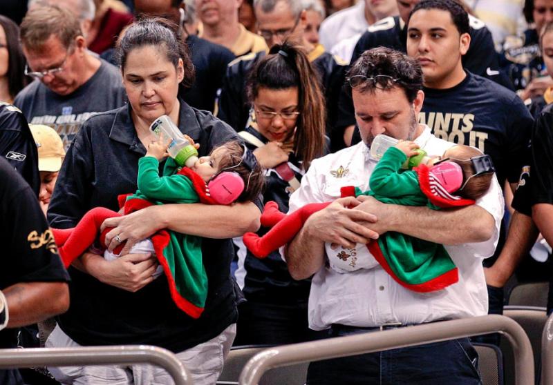 Fans in New Orleans hold their infant children during a moment of silence.