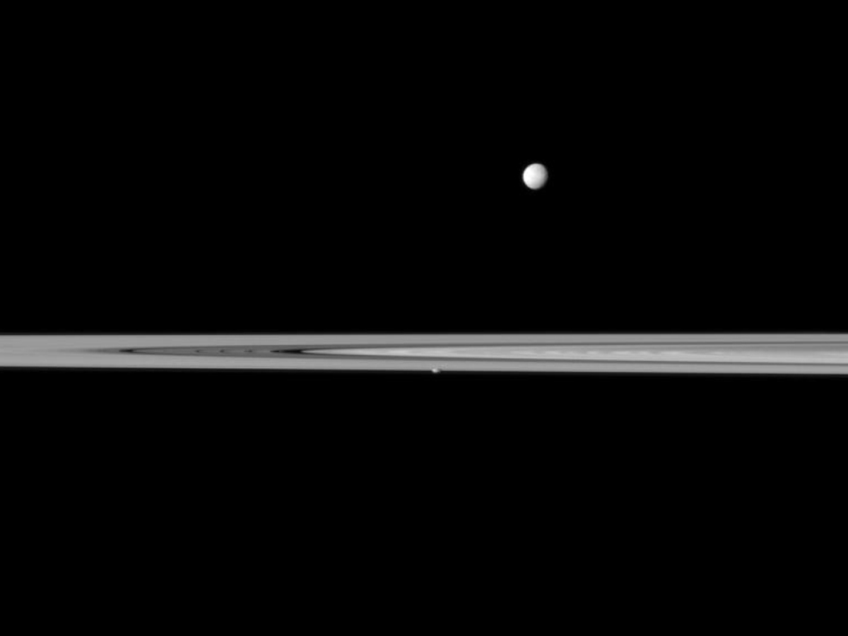 Saturn's small, potato-shaped moon Prometheus appears embedded within the planet's rings near the center of this Cassini spacecraft view while the larger moon Mimas orbits beyond the rings.