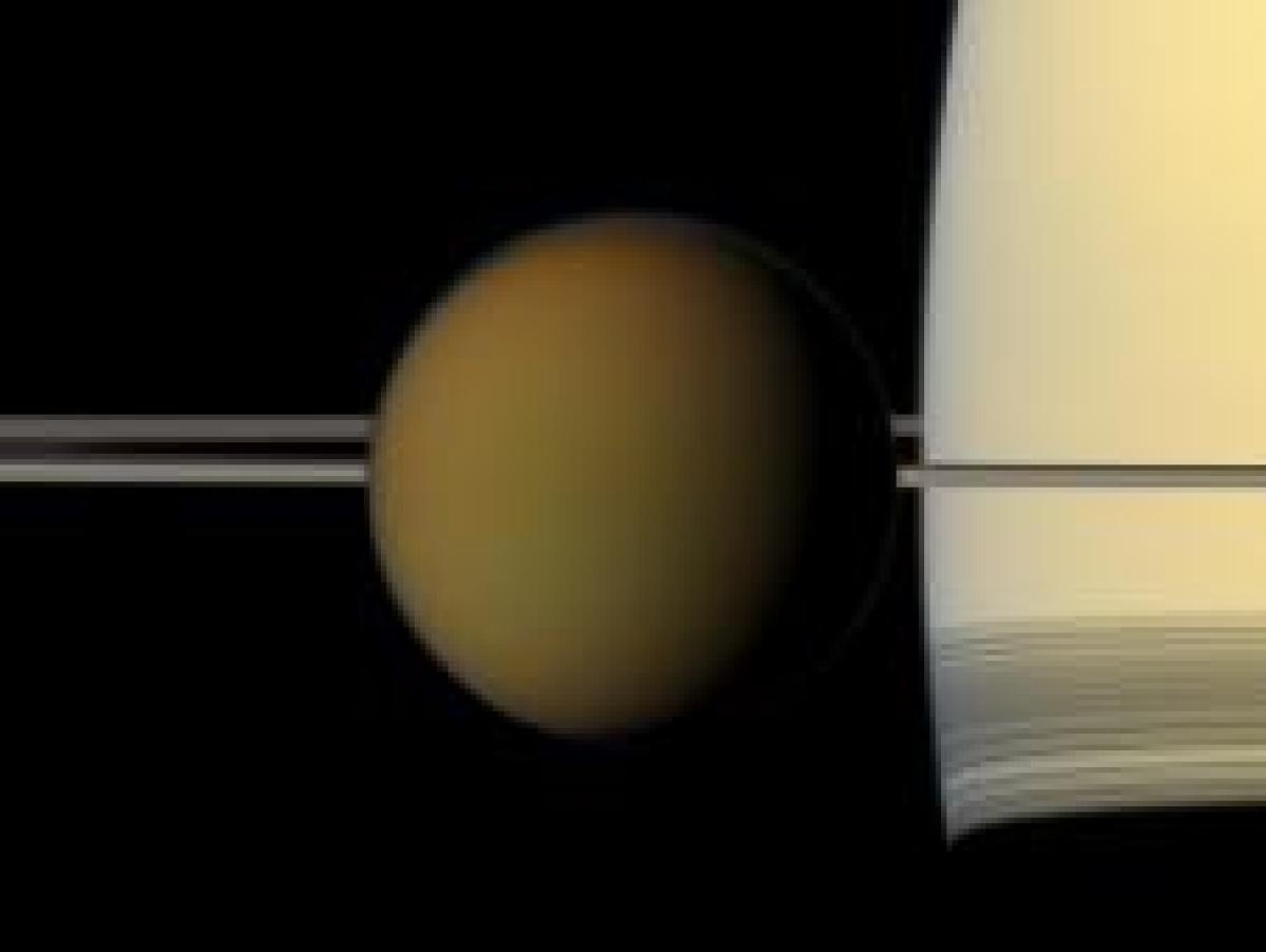 The colorful globe of Saturn's largest moon, Titan, passes in front of the planet and its rings in this true color snapshot.