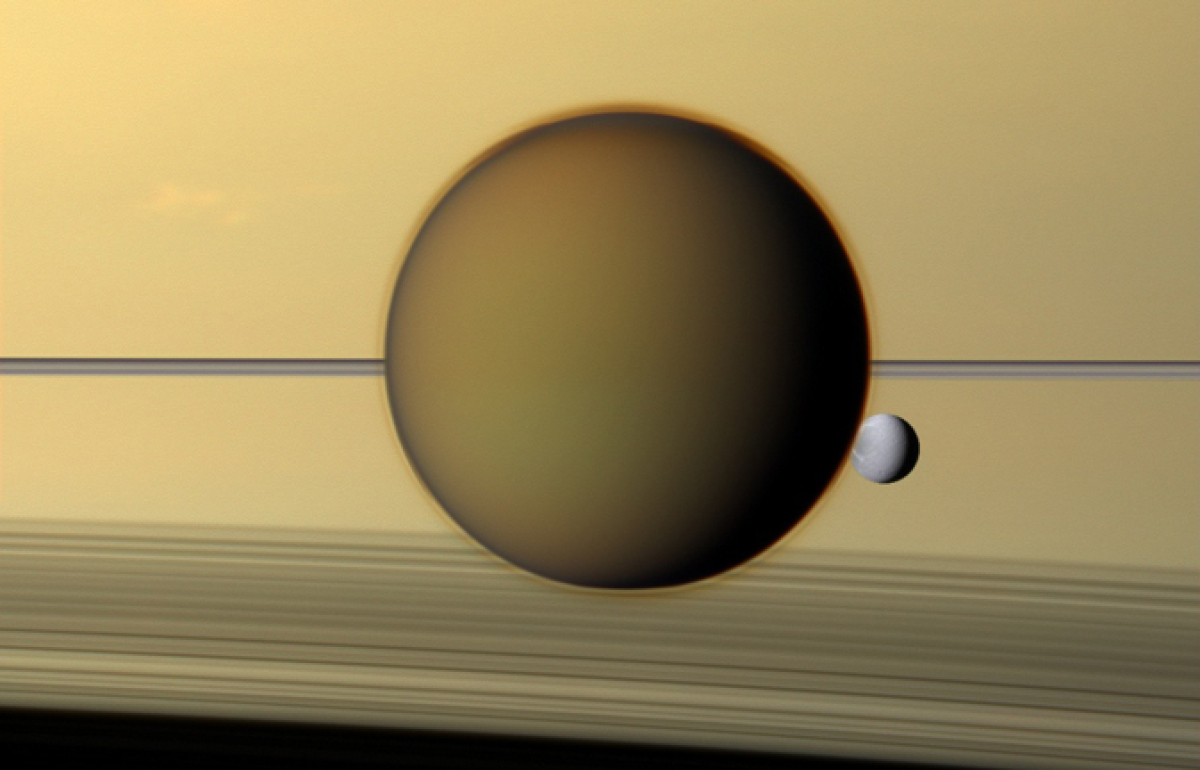 Saturn's third-largest moon Dione can be seen through the haze of its largest moon, Titan.
