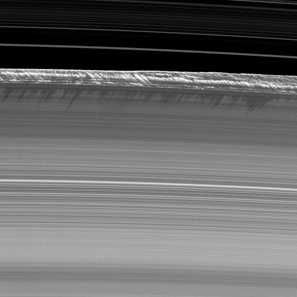 Vertical structures, among the tallest seen in Saturn's main rings, rise abruptly from the edge of Saturn's B ring to cast long shadows on the ring .
