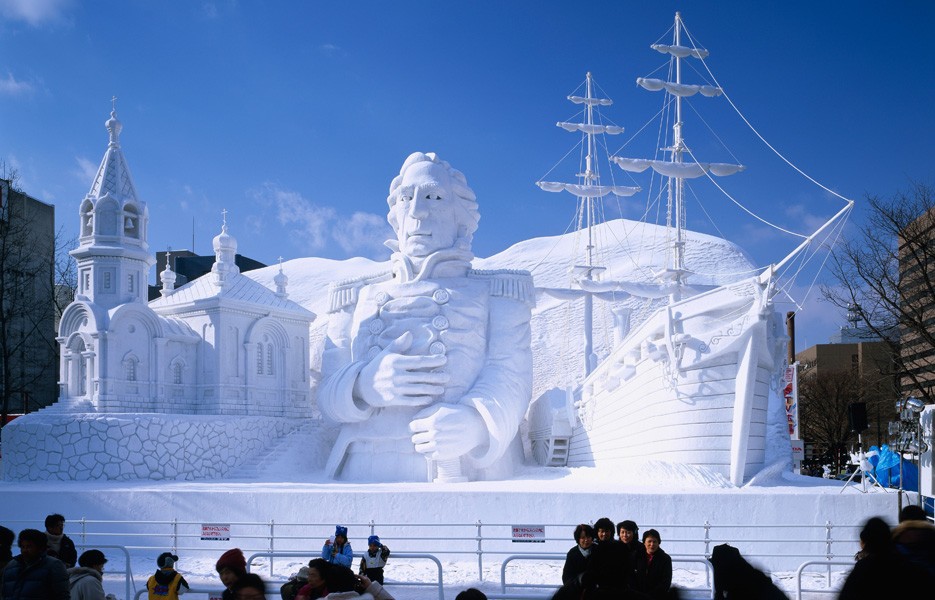 Visitors take photographs in front of a large-scale sculpture at the Sapporo Snow Festival in Sapporo, Hokkaido, Japan