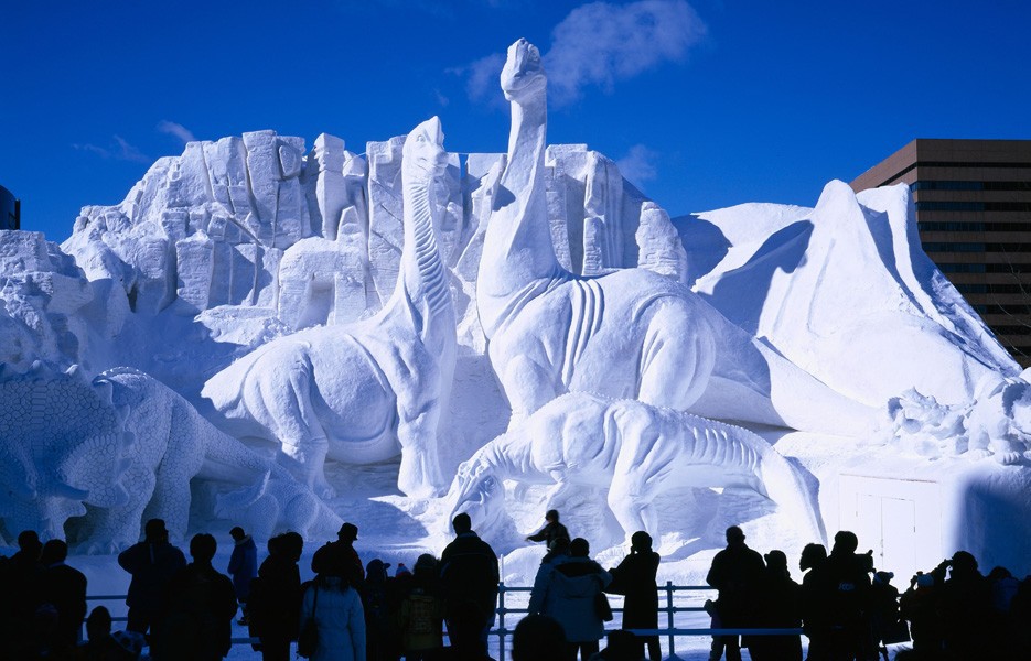 Tourists gather to view a sculpture of dinosaurs at The Sapporo Snow Festival in Sapporo, Hokkaido, Japan.