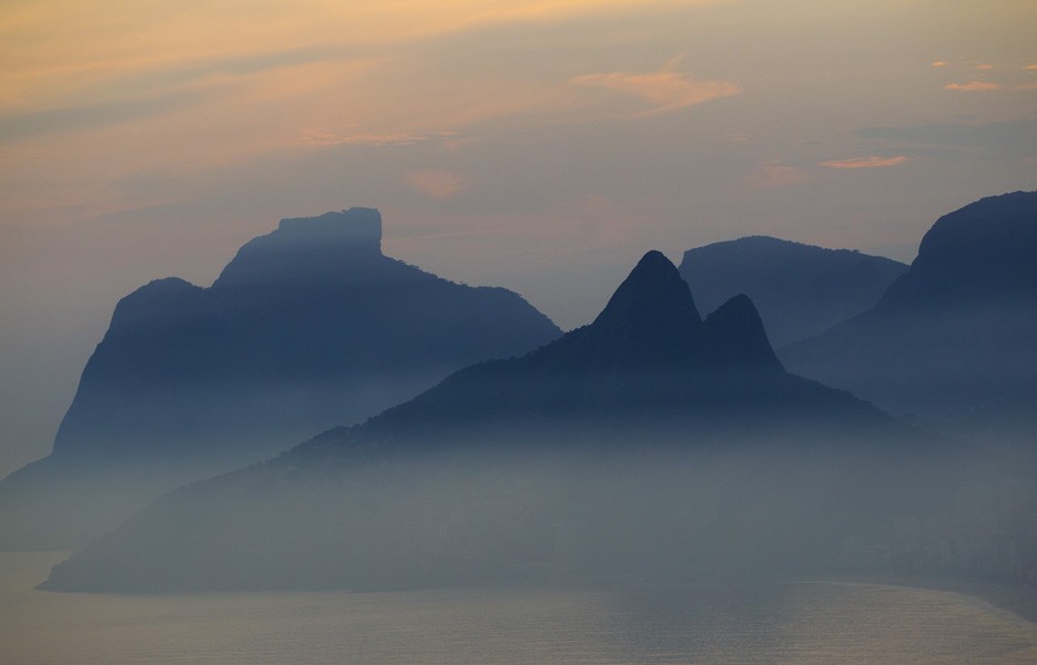 Morro Dois Irmaos front and Pedra da Gavea, or The Topsail rock are covered in fog at sunset in Rio de Janeiro, Brazil.