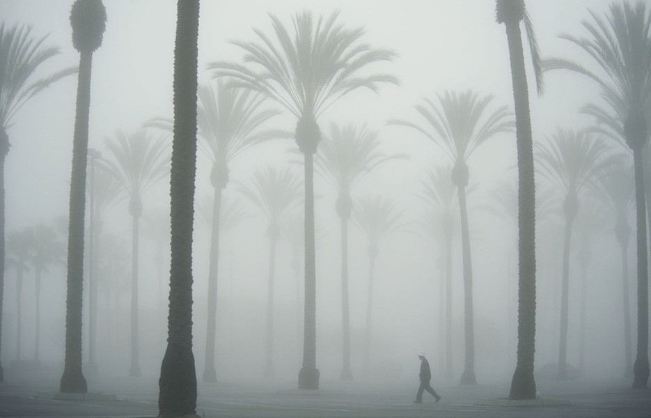 Thick fog covers the sky as a man walks through Buena Park Mall in Buena Park, Calif.