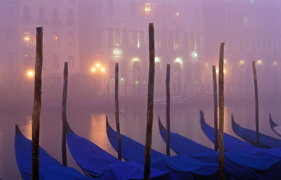 Dusk falls over gondolas moored in Venice's Grand Canal.